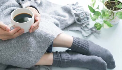 冷房で体が冷えている。ひざ掛けと温かい飲み物を飲む女性