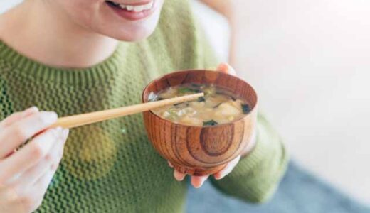 朝、女性がしょっぱそうなお味噌汁を飲もうとしている。