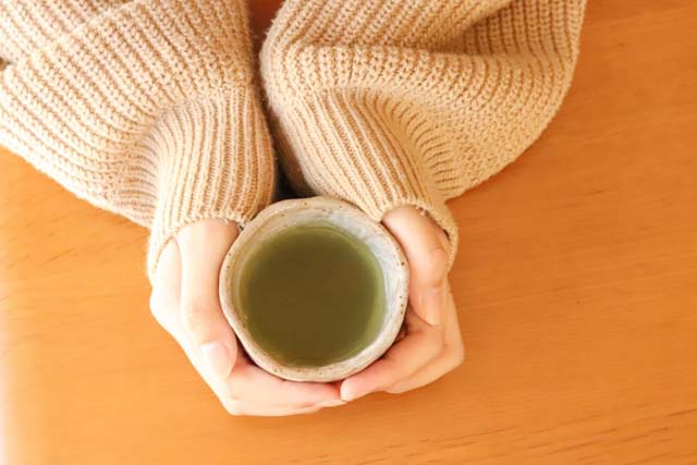 女性が両手で温かいお茶を持っている