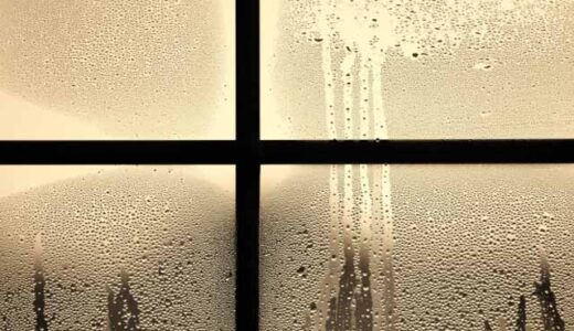 夕方、窓に雨が降りつけている。窓のガラスにはたくさんの水滴がついていて、外と中の寒暖差がある。