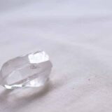 真っ白な布の上に透明な水晶のかけらが一粒置いてある。